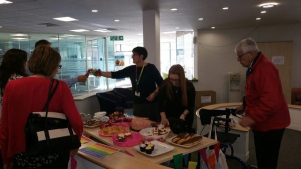 A table covered in cakes with people gathered around